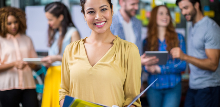 Portrait of smiling female executive holding clipboard and file in office