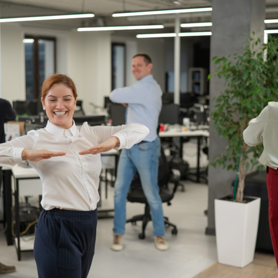 Four office workers warm up during a break. Employees do fitness exercises at the workplace